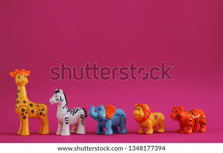 Five Plastic figurines of wild animals.Children's toy. Pink background.
Giraffe zebra elephant lion tiger