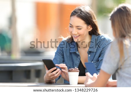 Happy woman checking smart phone online messages sitting in a park