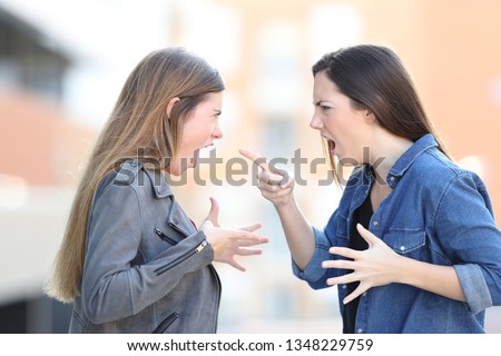 Two angry women fighting shouting each other in the middle of the street Royalty-Free Stock Photo #1348229759