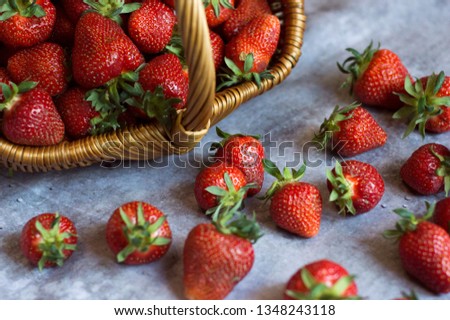 Strawberry basket.
Fresh ripe strawberries in a wicker basket and scattered on a gray rustic table.