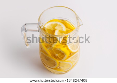 Cold, fresh, refreshing lemonade. Transparent glass jar full with lemon slices. Isolated on a white background.