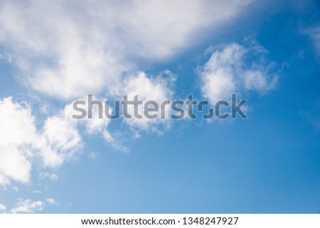 Fluffy white small clouds on the clear blue sky background. Copy space
