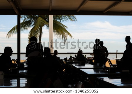 People silhouettes enjoying an afternoon in a bar in front of the beach in Vitoria, Espirito Santo, Brazil