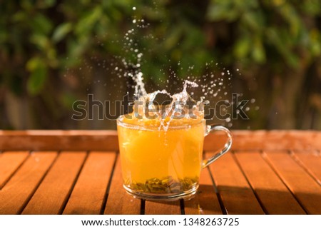 Splash of cool fresh tea with lemon in the transparent glass cup in the table outdoors 