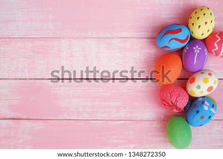 Colorful hand painted easter eggs with pink distress wooden background, pastel colors eggs, each with a unique pattern.