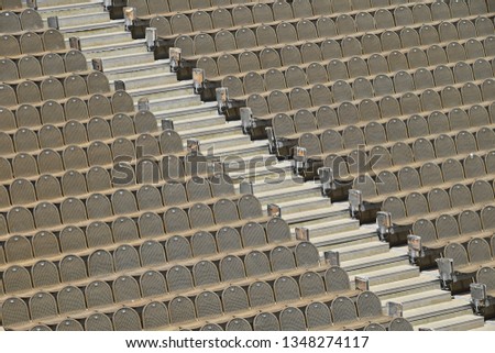 Rows of empty grey and red seats in open air concert hall auditorium, high angle side view