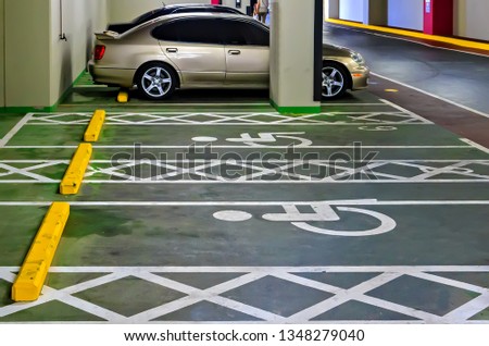 Many cars in parking, underground garage white marking lines on asphalt Handicapped parking spot