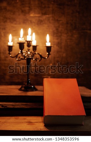 Holy Bible and candle on a old oak wooden table. Beautiful gold background. Religion concept. 