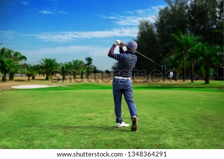 Golfer hitting golf shot with club on course vintage color tone, Man playing golf on a golf course in the sun, Golfers hit sweeping golf course in the summer