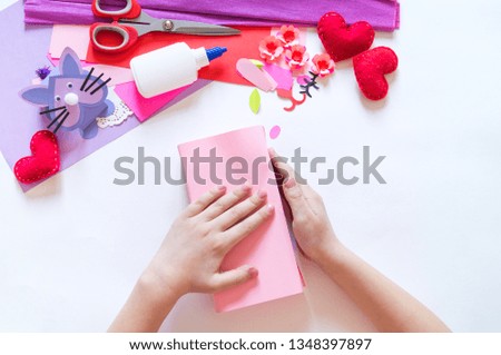 Child hands making a box rabbit. Holiday Easter light. Material for creative. White background.