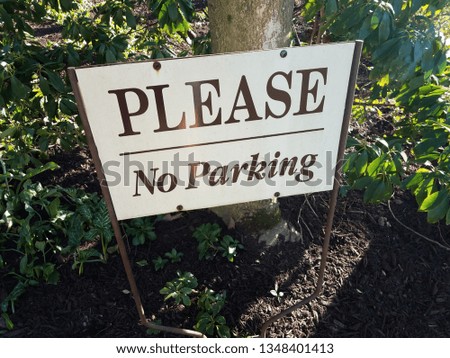 white please no parking sign and green leaves and plants