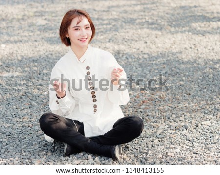 Beautiful young brunette woman in white shirt sit and enjoy music in sunny day. Outdoor fashion portrait of glamour Chinese cheerful stylish girl, emotions, people, beauty and lifestyle concept.