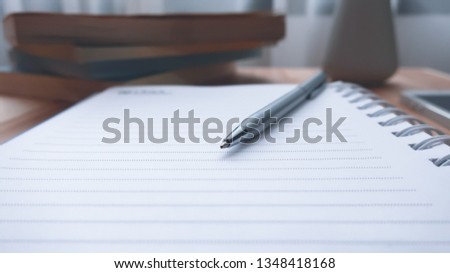 a pen on blank of notebook is open on wooden table