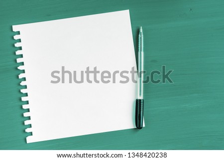 A blank sheet of paper and a pen on a green wooden background.