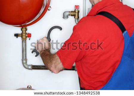 working man with wrench is mounting in heating room
