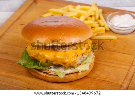Homemade burger with fish, cheese and salad leaves served potato and white sauce