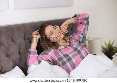 Young woman with headphones enjoying music in bed