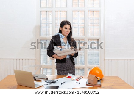 Asian woman architect with blueprint in hand and yellow helmet with select focus and use effect filter. Concept Engineer and business work.