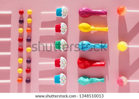 Children's cheerful decor for a party, pink background. Sweet candies, bright balls, festive candles and straws.