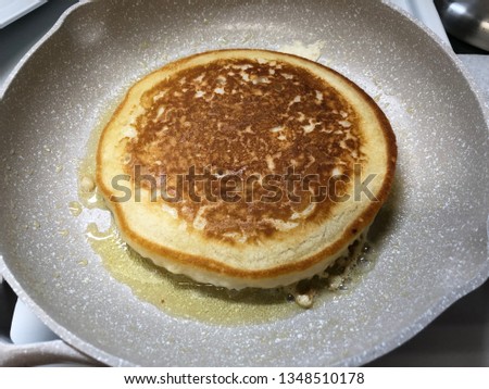 Closeup of a brown thick pancake fried in a pan. Pancake is a thin flat cake of batter, usually fried and turned in a pan, and is usually eaten with syrup or rolled up with a filling.