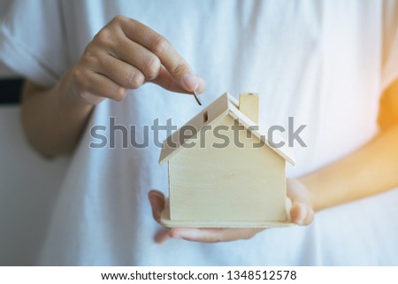 Coins stack with hand putting of coin on home model bank,Finance and money saving concept