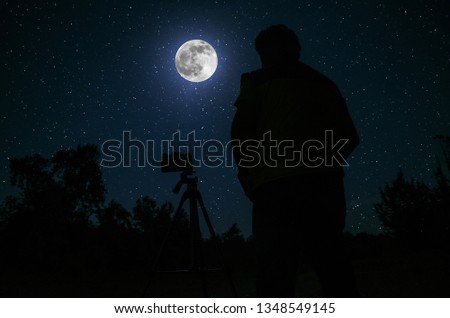 Silhouette of photographer standing with camera on tripod over Night sky with star background. Selective focus