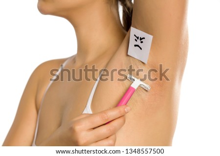 Woman shaves her underarm with a sad face on her on white background