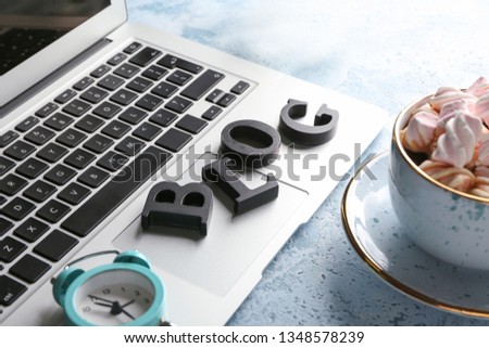 Word BLOG with laptop, cup of coffee and alarm clock on table