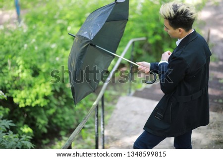 Spring Park in rainy weather and a young man with an umbrella
