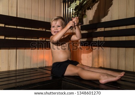 Portrait of cute little boy relaxing with a broom at sauna in Russia. Tipical russian rest