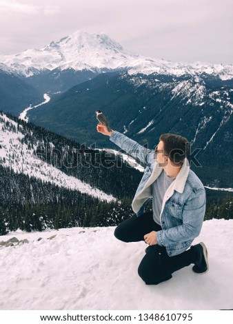 male traveler holds a bird in his hands in the snowy mountains. Jeanswear in winter