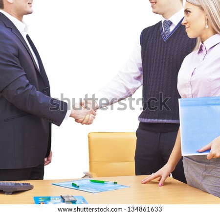 Handshake business partners in the office after the signing of important documents - two people on one side and one on the other  isolated on white background