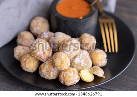Famous Canary Islands dish, Papas Arrugadas (wrinkly potatoes with salt) and Mojo picon (red  spicy sauce) on wood table in local restaurant. Royalty-Free Stock Photo #1348626791