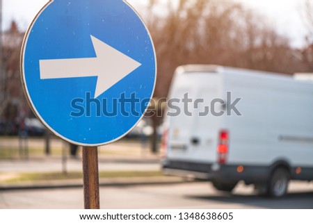 Proceed in direction arrow traffic sign on the street with defocussed vehicle in background