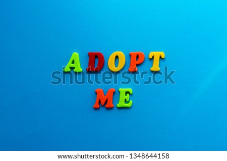 text adopt me from plastic colored letters on blue paper background