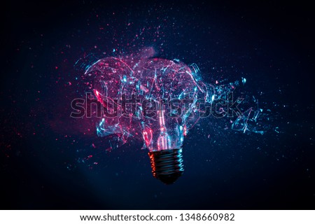Detail of a tungsten filament electric light bulb photographed in the exact moment that is hit by a bullet, High speed studio photography. Royalty-Free Stock Photo #1348660982