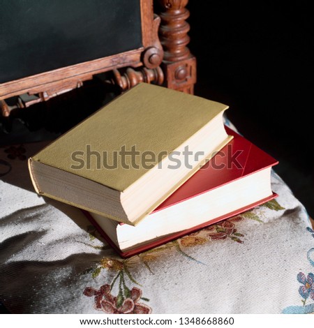 Sunlight on the two books laid on the vintage carved wooden chair, square indoor shot