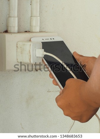 Close up of persons hands playing a game and Charging battery on a smartphone