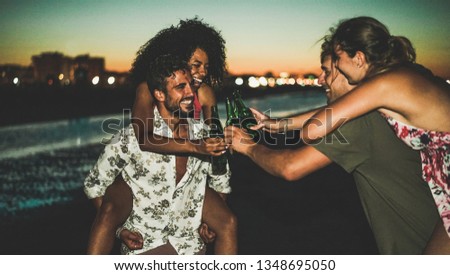 Happy friends drinking beer and having fun on the beach after sunset - Young people enjoying summer vacation - Youth,holidays,party and friendship concept - Soft focus on left guys faces