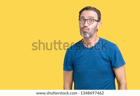 Handsome middle age hoary senior man wearin glasses over isolated background making fish face with lips, crazy and comical gesture. Funny expression.