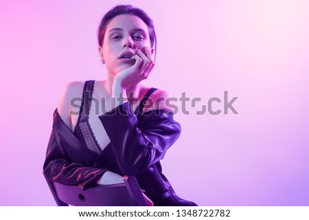 Cinematic night portrait of woman in  neon. High Fashion model girl in colorful bright neon lights posing in studio, portrait of beautiful woman in   jacket, underwear and trousers. 