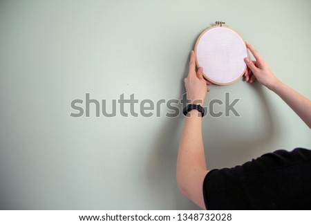 young woman holding canvas frame on wall. house decoration concept. space for your design.