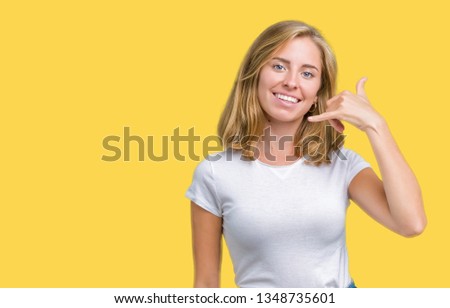 Beautiful young woman wearing casual white t-shirt over isolated background smiling doing phone gesture with hand and fingers like talking on the telephone. Communicating concepts.
