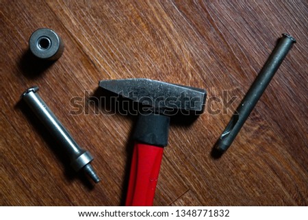 Red Hammer and Rivet joint tool with rivets on brown background
