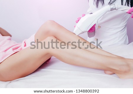 Beautician removes hair on beautiful female legs using a laser