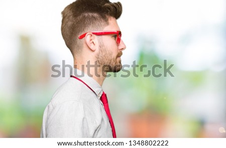 Young handsome business man wearing glasses looking to side, relax profile pose with natural face with confident smile.
