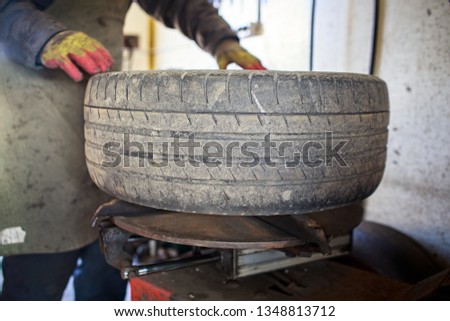 Professional car mechanic replace tire on wheel in auto repair service