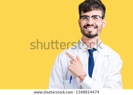 Young professional scientist man wearing white coat over isolated background cheerful with a smile of face pointing with hand and finger up to the side with happy and natural expression on face