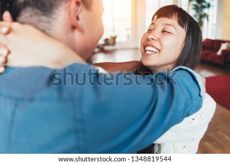 Happy young family couple playing fool, dancing and spinning together at home, bright loft apartment