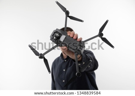 A man in a blue shirt holding a quadcopter on a white background